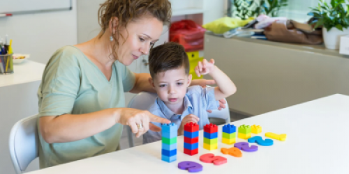 a teacher helps a student with blocks